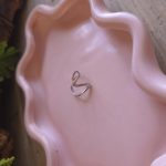 Zilverkleurige verstelbare open V-ring op een roze sieradenschaaltje