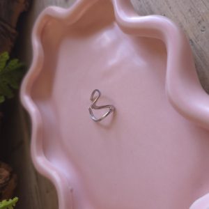 Zilverkleurige verstelbare open V-ring op een roze sieradenschaaltje