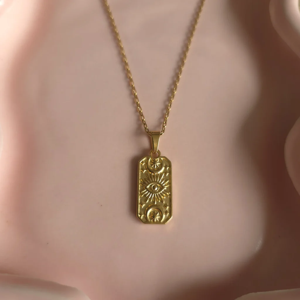 Goudkleurige ketting met rechthoekige reliëfhanger van dichtbij
